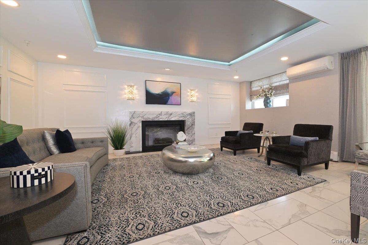 320 East Shore Road, Unit 4C Great Neck, NY 11023 - Photo 6 of 31 Living area featuring a tray ceiling, light marble finish flooring, a fireplace, a wall mounted AC, and recessed lighting