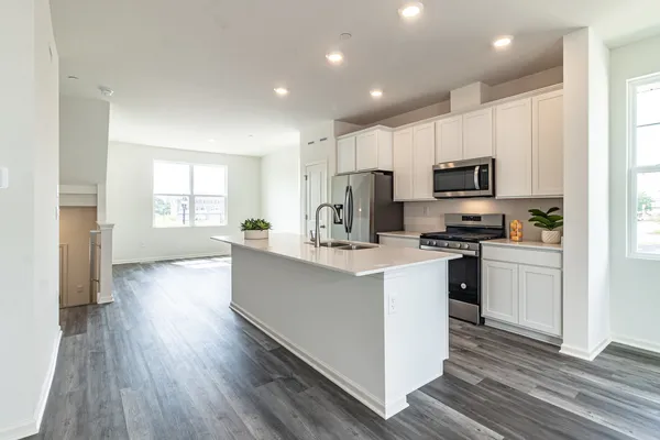 a kitchen with kitchen island wooden floors white cabinets appliances and a window