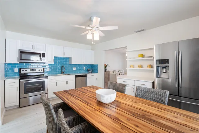 a kitchen with stainless steel appliances wooden floor dining table and chairs