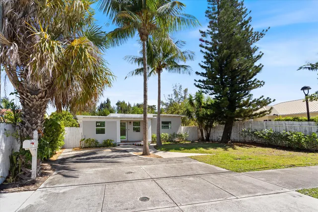 a view of a house with a yard and palm trees