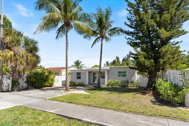 a view of a house with a yard and palm trees