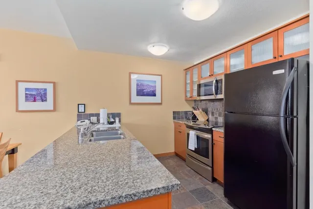 a kitchen with stainless steel appliances granite countertop a refrigerator a stove and a sink