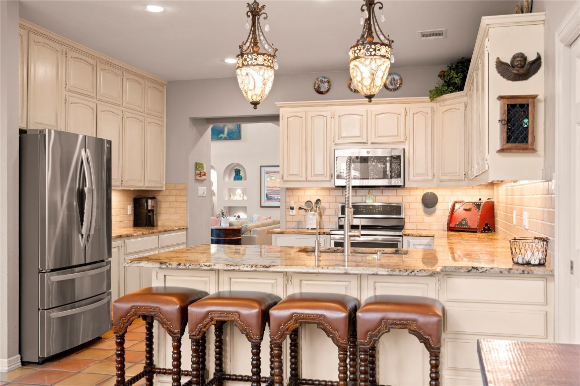 5229-5012 Hupedo Ranch Road Spicewood, TX 78669 - Photo 9 of 40 a kitchen with granite countertop a refrigerator a stove a sink dishwasher a dining table and chairs with wooden floor