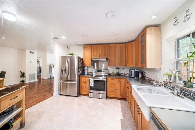a large kitchen with stainless steel appliances a refrigerator sink and cabinets