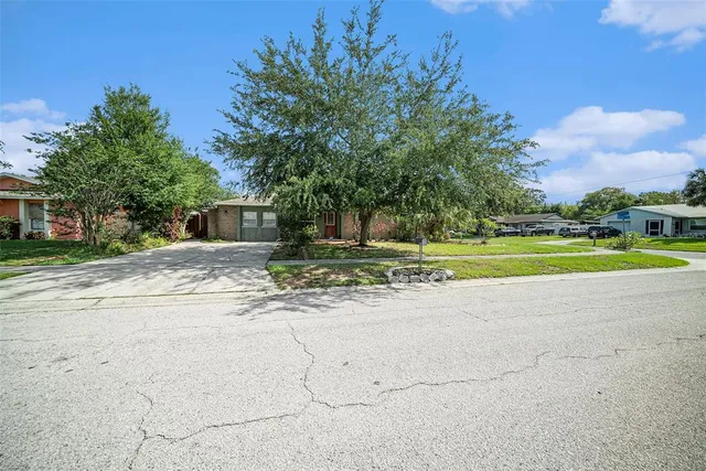 a view of a house with a big yard and large trees