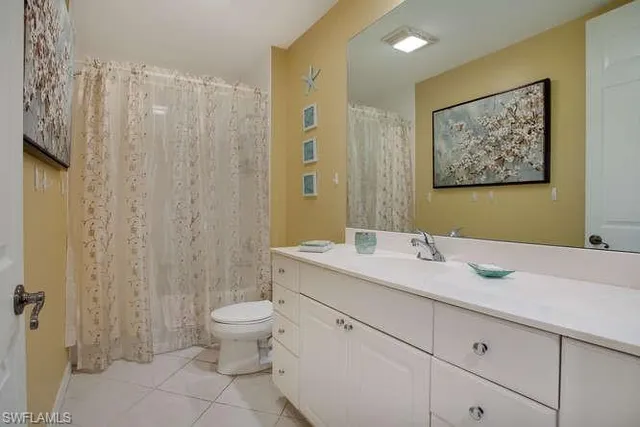 a bathroom with a granite countertop sink a toilet and a mirror