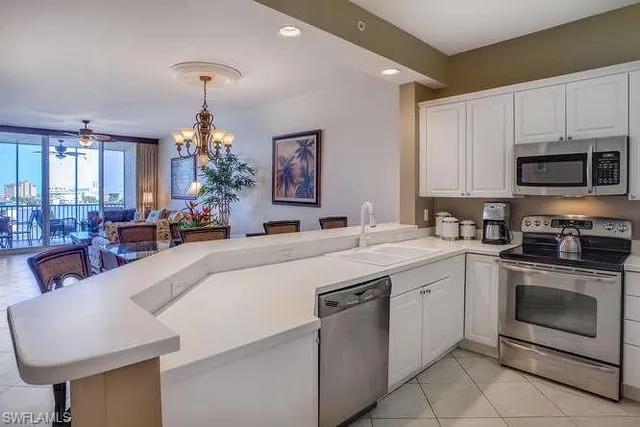 a large kitchen with stainless steel appliances a stove a sink a oven a dining table and chairs