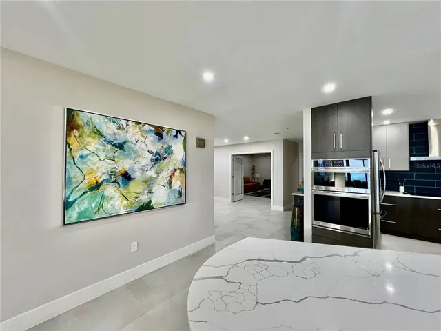 a large white kitchen with stainless steel appliances kitchen island granite countertop a refrigerator and a stove top oven