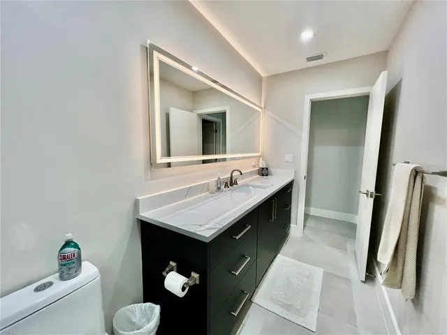 a bathroom with a sink vanity granite and toilet