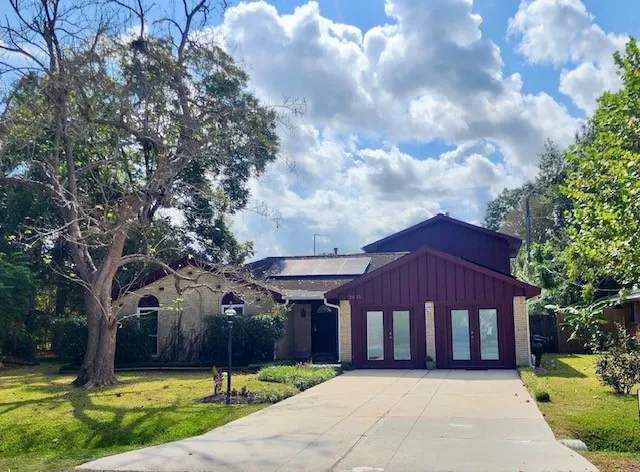 a front view of a house with a garden and trees
