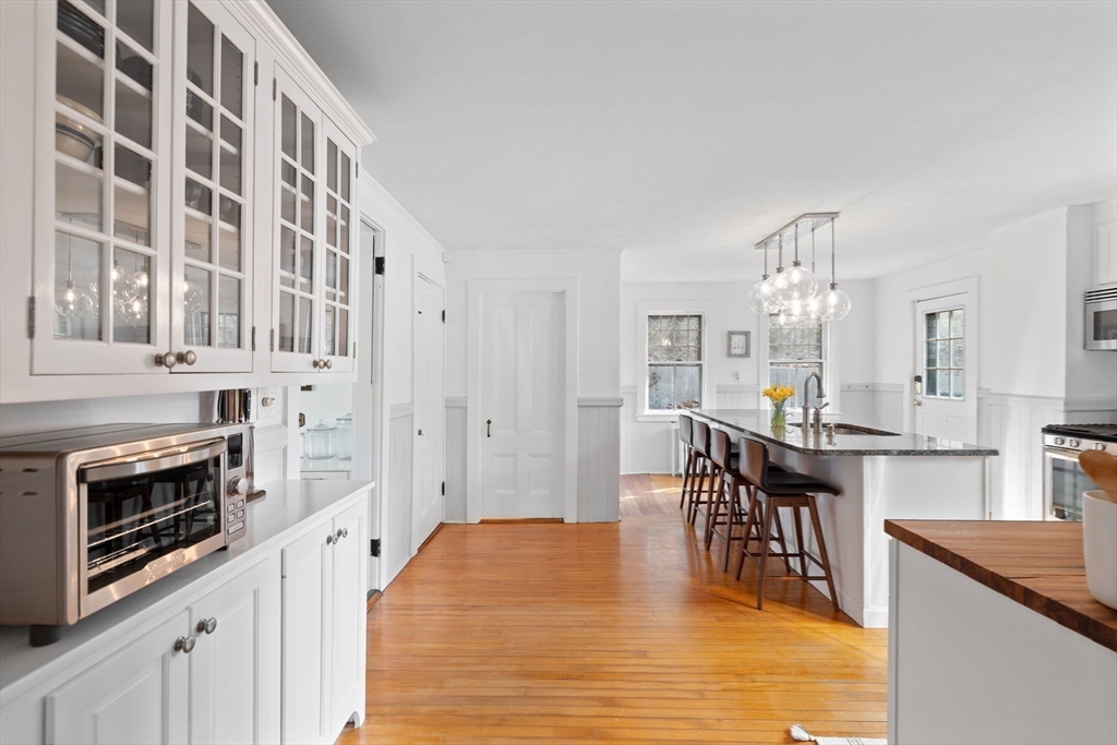 118 Main Street Sandwich, MA 02563 - Photo 7 of 41 a kitchen with stainless steel appliances granite countertop a stove top oven a sink a dining table and chairs with white cabinets