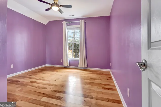 an empty room with windows and fan chandelier fan
