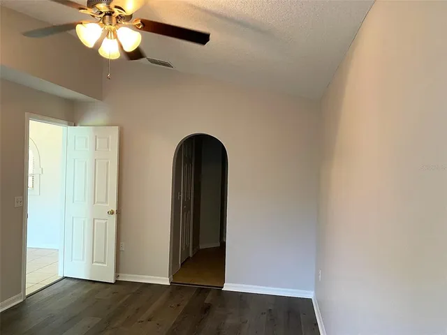 an empty room with wooden floor fan and window