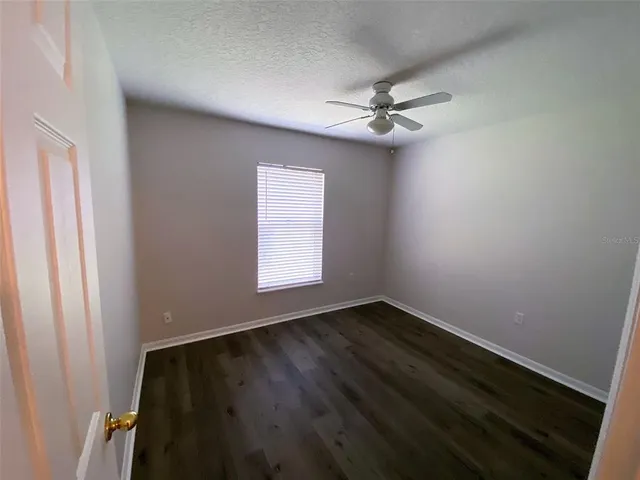 an empty room with windows and fan