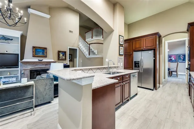 a kitchen with stainless steel appliances granite countertop a refrigerator a stove and a sink with wooden floor