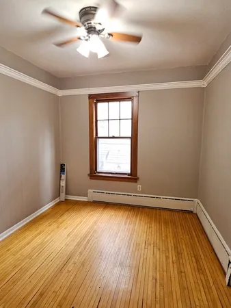 a view of empty room with wooden floor and fan