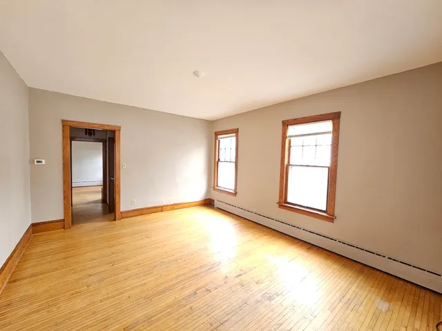 a view of an empty room with a window and wooden floor