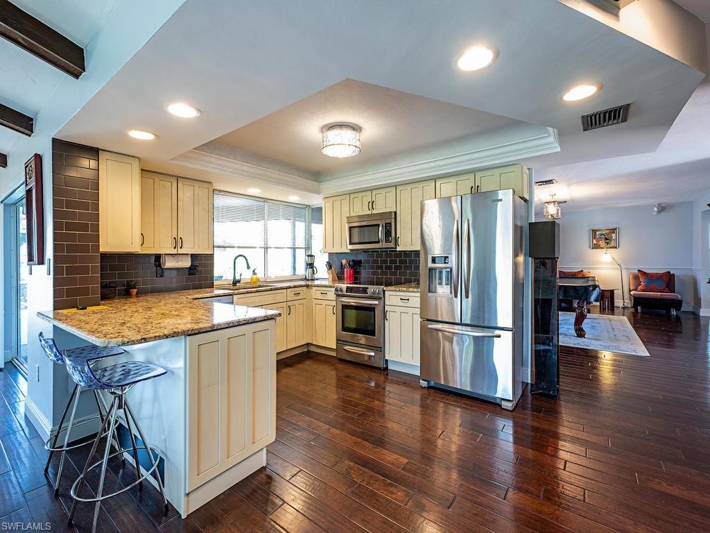 478 Torrey Pines Point Naples, FL 34113 - Photo 3 of 16 a kitchen with stainless steel appliances granite countertop a refrigerator a stove top oven a sink dishwasher and white cabinets with wooden floor