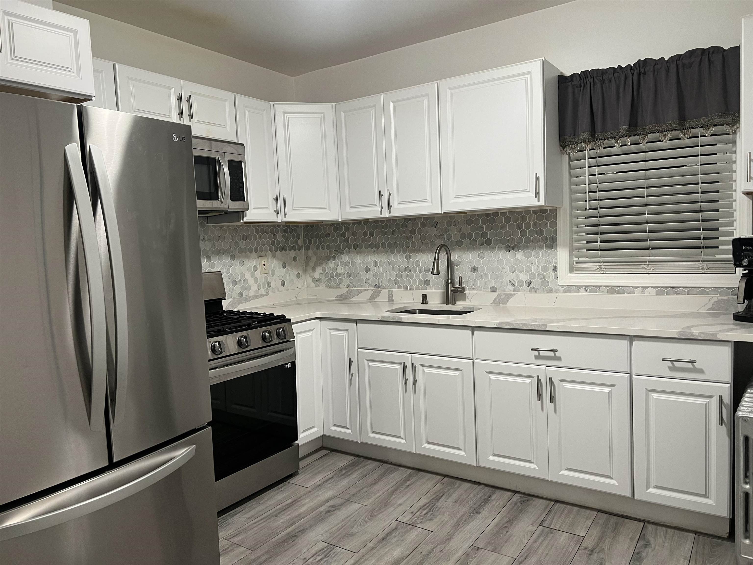 6126 Washington Street, Unit 2 West New York, NJ 07093 - Photo 3 of 7 a kitchen with stainless steel appliances granite countertop a refrigerator sink and cabinets