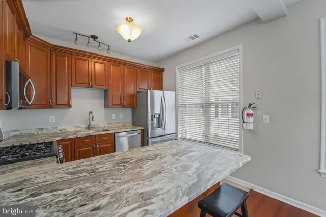 a kitchen with stainless steel appliances granite countertop a sink refrigerator and cabinets