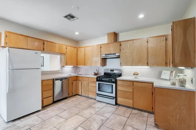 a kitchen with stainless steel appliances granite countertop a sink stove refrigerator and cabinets