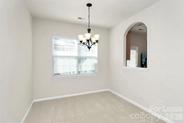 an empty room with a window and chandelier