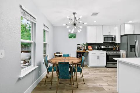 a kitchen with a dining table chairs and refrigerator