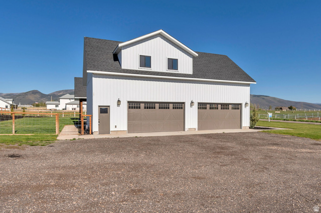 1820 West Farmhouse Flats Road Peoa, UT 84061 - Photo 55 of 79 White board and batten exterior featuring a two-car garage with carriage-style doors, an upper dormer with two windows, and a side entry door