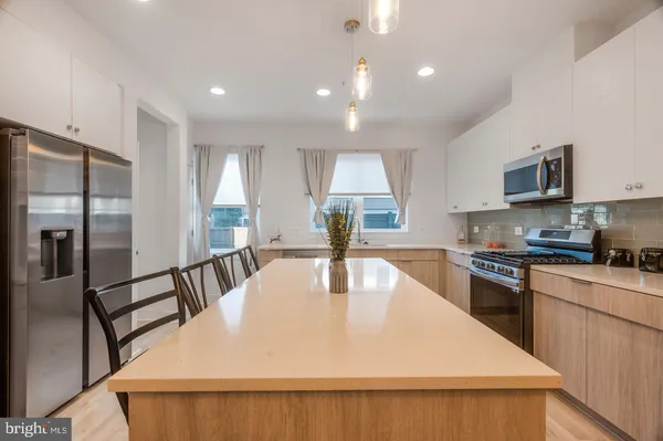 a kitchen with stainless steel appliances kitchen island granite countertop a refrigerator a stove top oven a sink and dishwasher