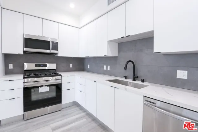 a kitchen with stainless steel appliances granite countertop a sink a stove a microwave and cabinets