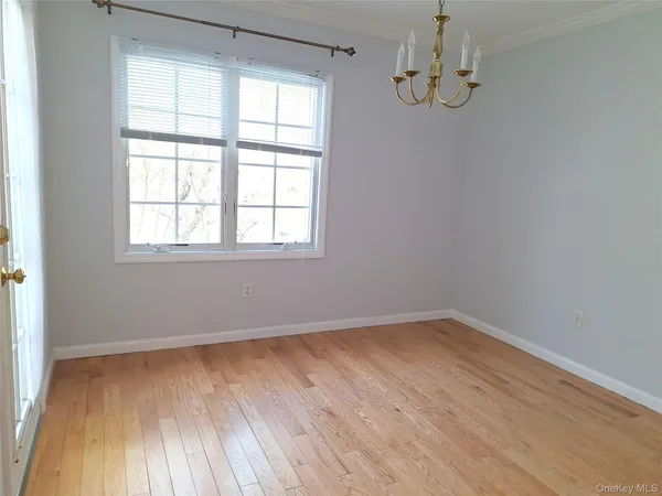 a view of an empty room with wooden floor and closet