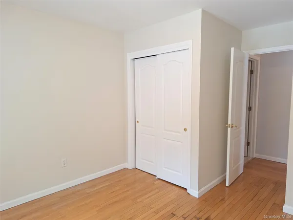 a view of an empty room with wooden floor and closet