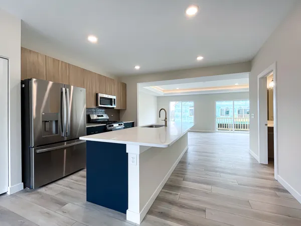 a large kitchen with stainless steel appliances wooden floor and a refrigerator