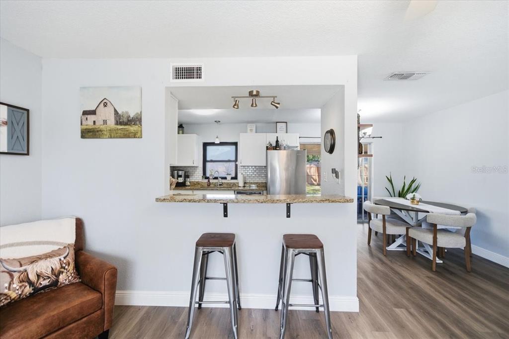 3487 Begonia Place Largo, FL 33771 - Photo 11 of 34 a kitchen with stainless steel appliances a dining table chairs and wooden floor