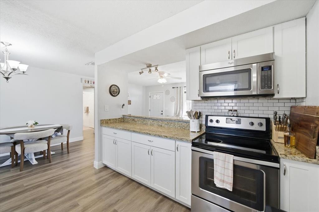 3487 Begonia Place Largo, FL 33771 - Photo 16 of 34 a kitchen with stainless steel appliances kitchen island granite countertop a stove a sink and a microwave