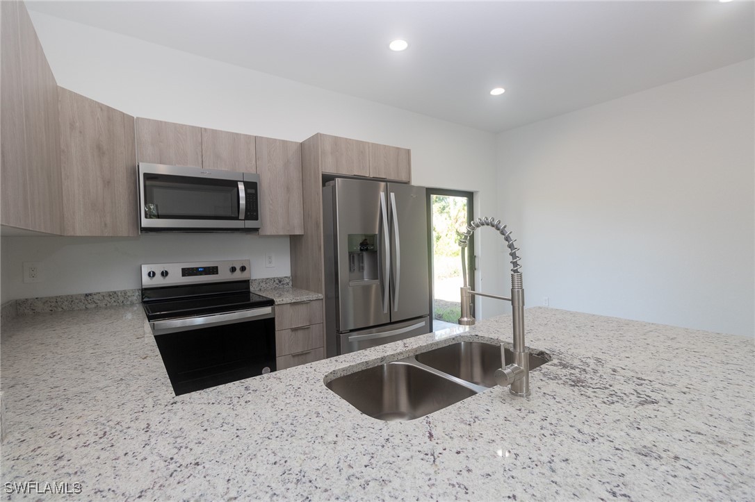 3105 Myra Lane LaBelle, FL 33935 - Photo 6 of 29 a kitchen with granite countertop a refrigerator and a sink