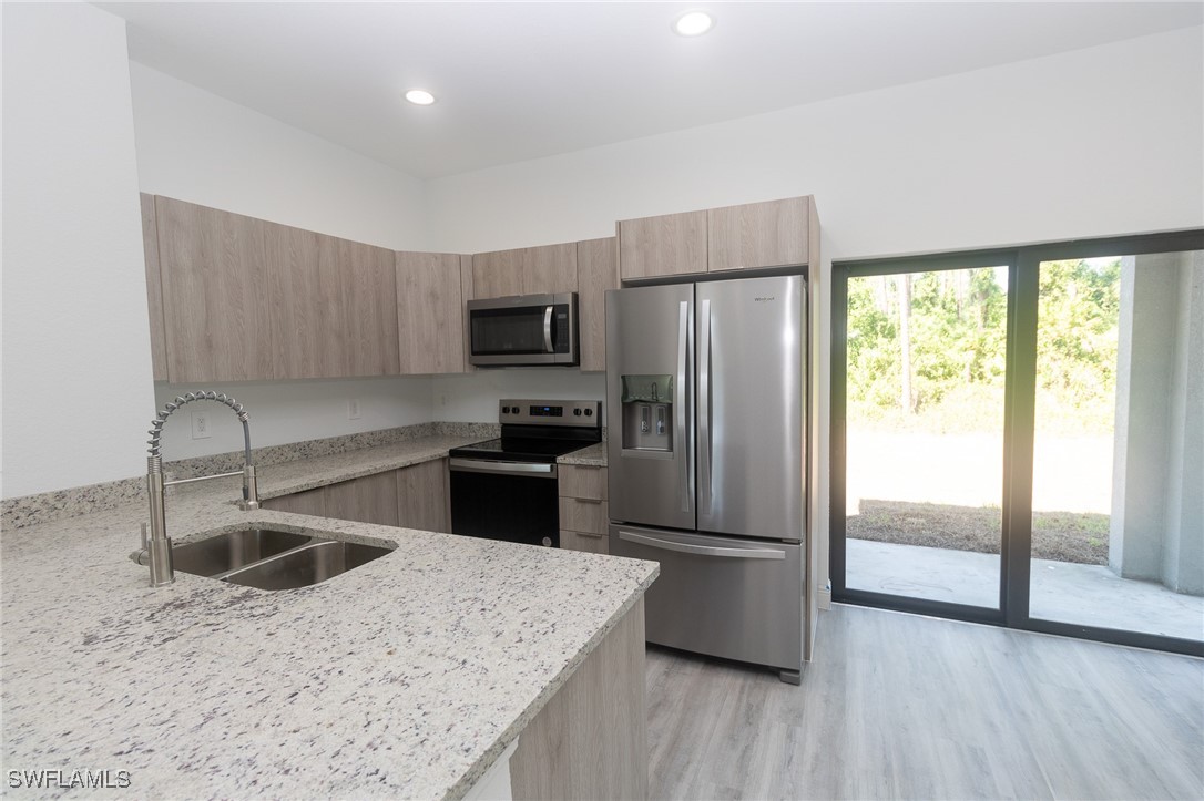 3105 Myra Lane LaBelle, FL 33935 - Photo 8 of 29 a kitchen with a refrigerator a microwave a sink and a stove with wooden floor