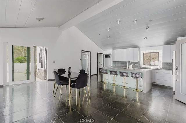 a kitchen with white cabinets and chairs