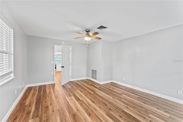 a view of a room with wooden floor and a ceiling fan