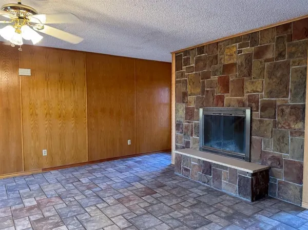 a view of an empty room with a fireplace and a fan
