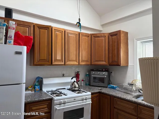 a kitchen with granite countertop a stove a sink and a refrigerator
