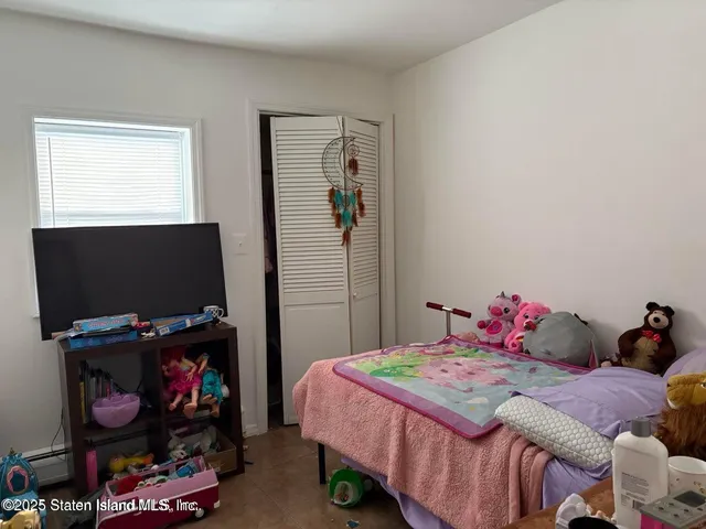 a bedroom with a bed a flat screen tv and a window