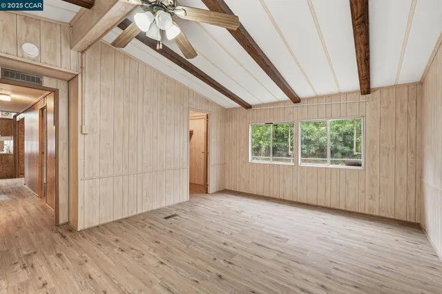 an empty room with wooden floor front door and windows