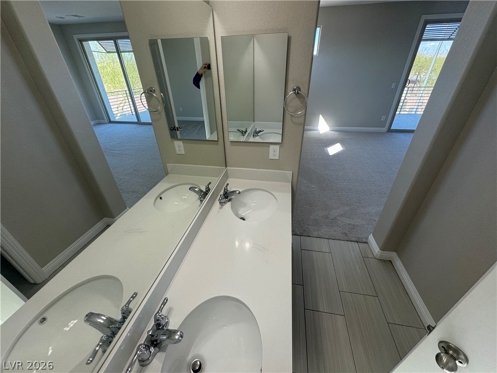 1051 East Sunset Road Henderson, NV 89011 - Photo 17 of 36 Full bath with double vanity, light carpet, and a textured wall