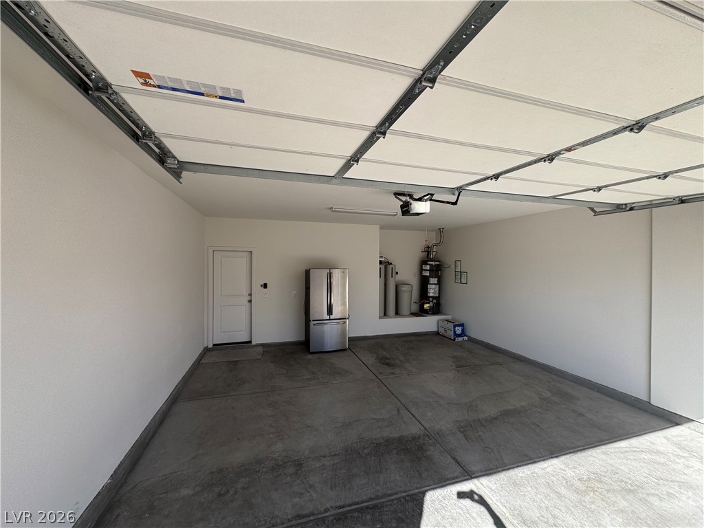 1051 East Sunset Road Henderson, NV 89011 - Photo 31 of 36 Garage featuring freestanding refrigerator, water heater, and a garage door opener