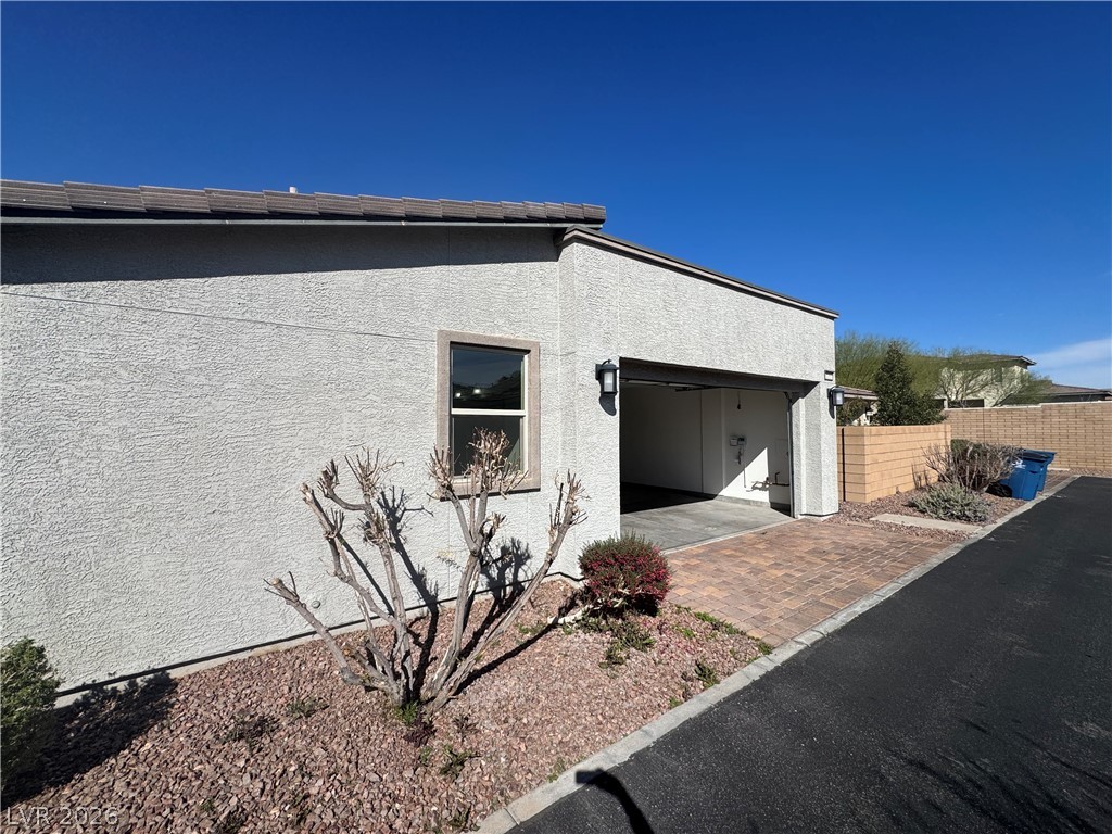 1051 East Sunset Road Henderson, NV 89011 - Photo 32 of 36 View of side of home with stucco siding, an attached garage, decorative driveway, and a patio