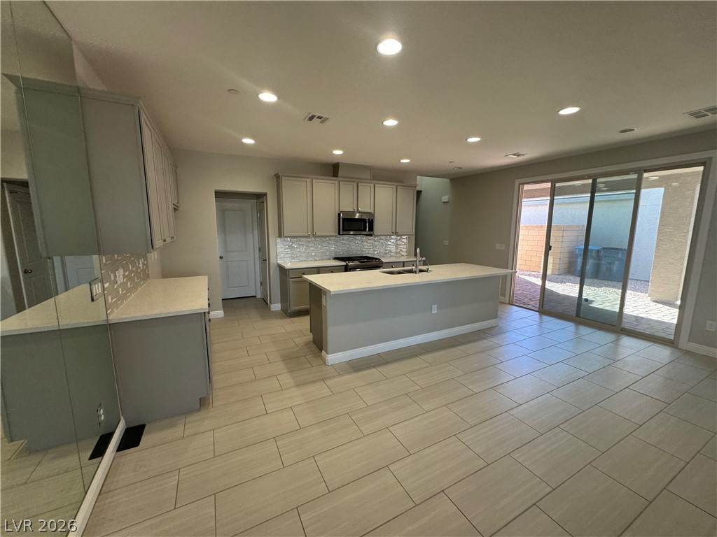 1051 East Sunset Road Henderson, NV 89011 - Photo 4 of 36 Kitchen featuring gray cabinetry, light stone counters, recessed lighting, decorative backsplash, and stainless steel appliances