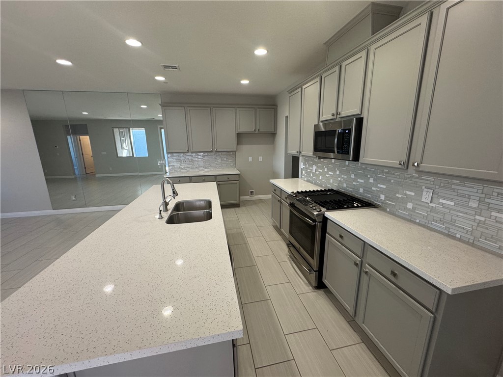 1051 East Sunset Road Henderson, NV 89011 - Photo 9 of 36 Kitchen with stainless steel appliances, gray cabinetry, light stone countertops, tasteful backsplash, and recessed lighting