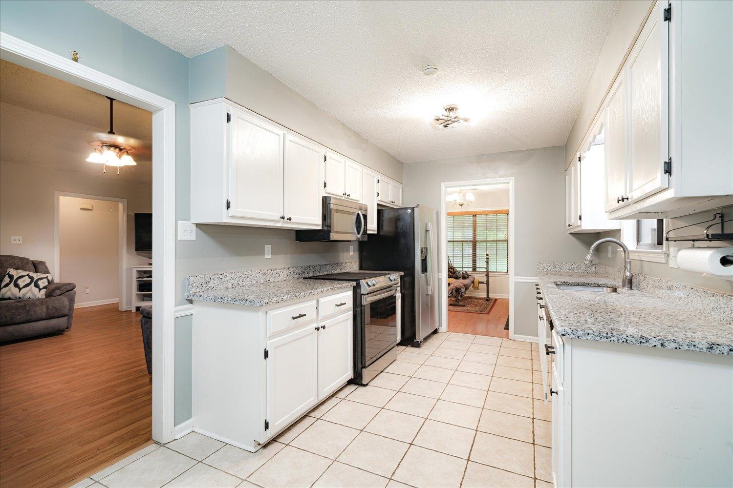 8035 Jack Bond Road Arlington, TN 38002 - Photo 14 of 24 Kitchen featuring a sink, appliances with stainless steel finishes, light tile patterned flooring, white cabinets, and a textured ceiling
