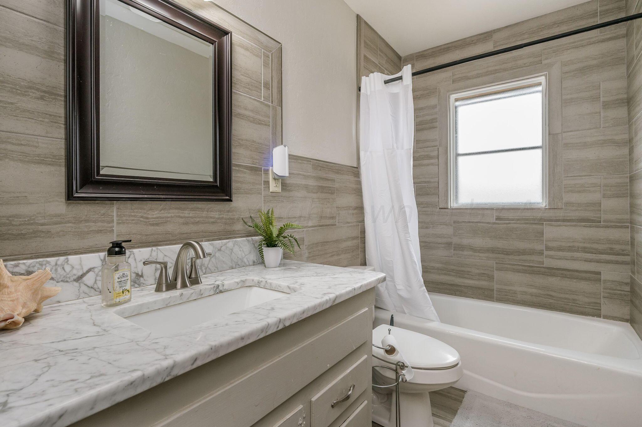 4205 South Bonham Street Amarillo, TX 79110 - Photo 14 of 24 a bathroom with a granite countertop sink mirror vanity bathtub and a toilet